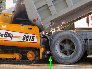 The paver pushes the truck along